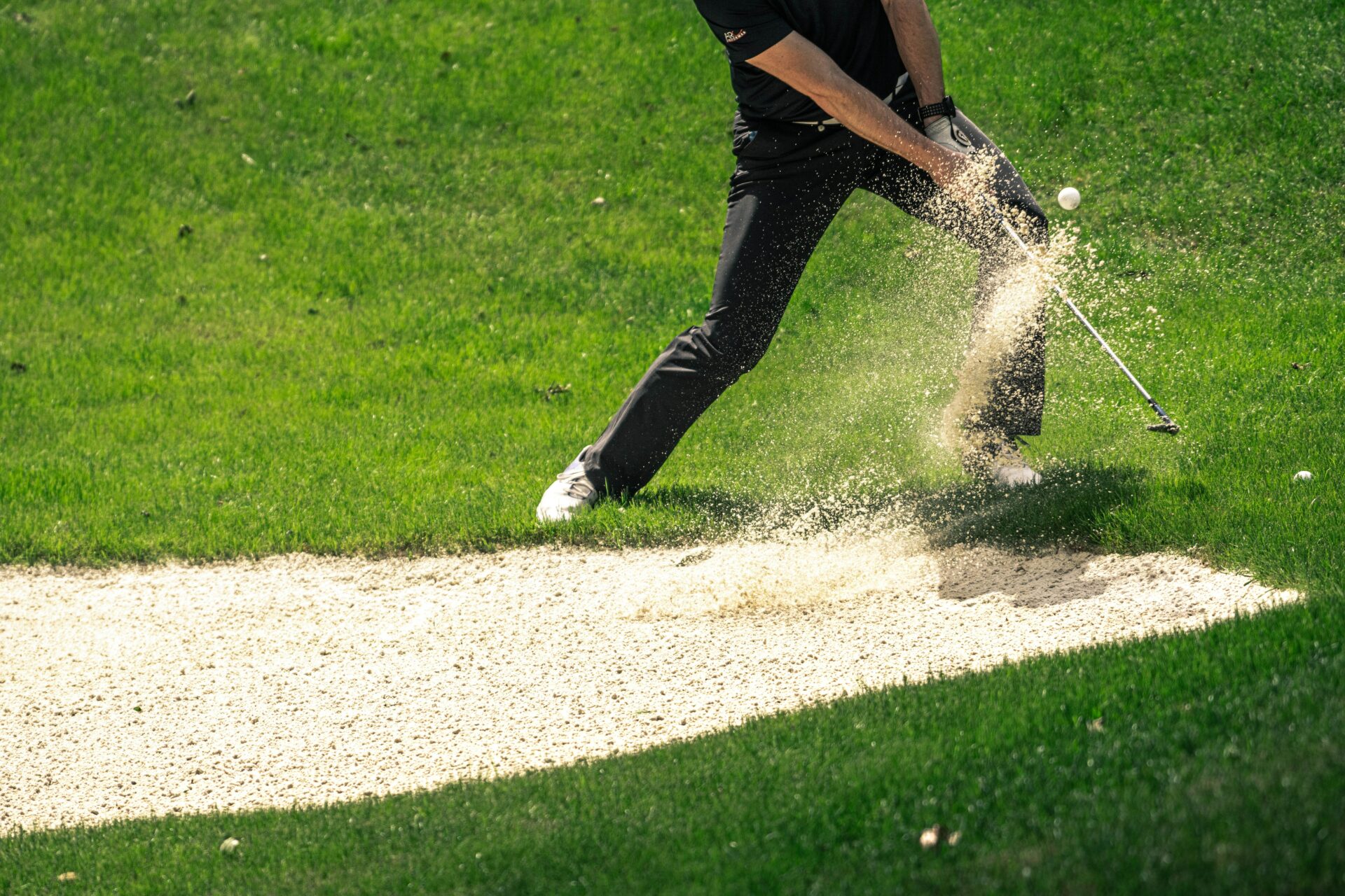 Golfer schlägt Ball aus Sand mit einem Sand-Wedge